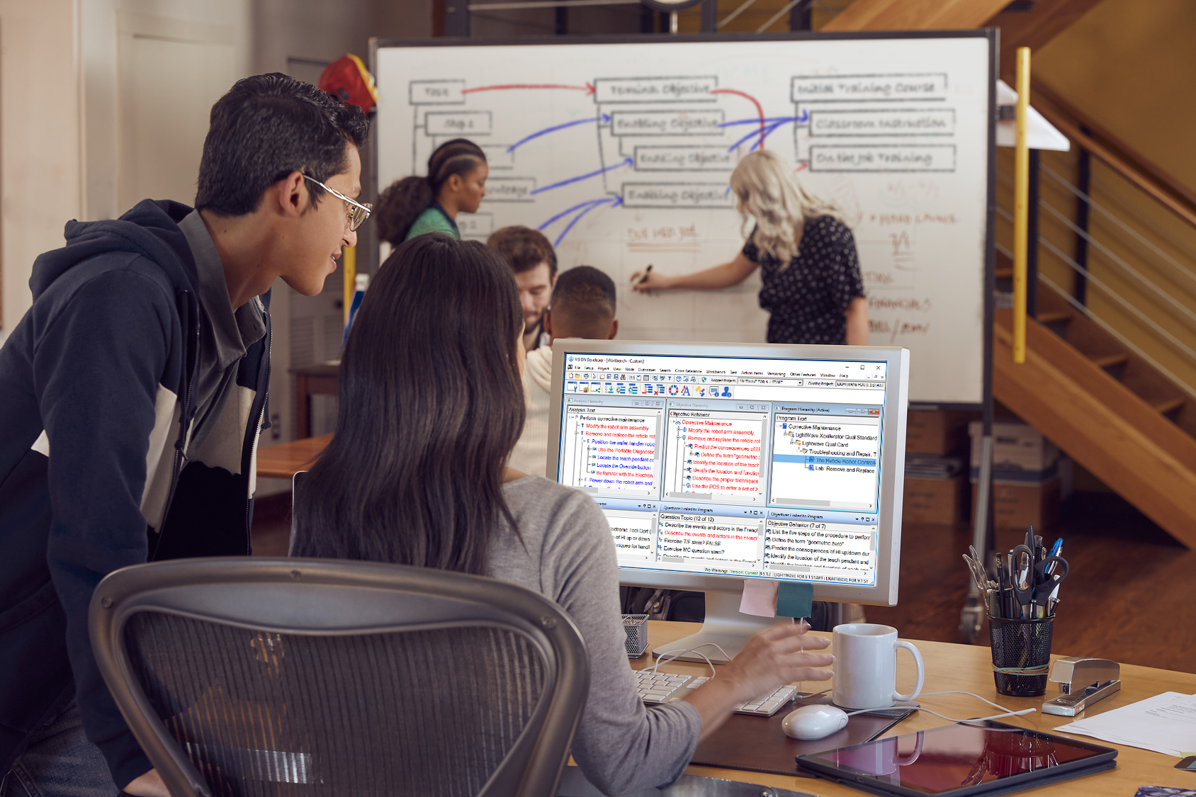 A collaborative work environment with a diverse group of individuals focused on a large monitor displaying the VISION Developer software interface.