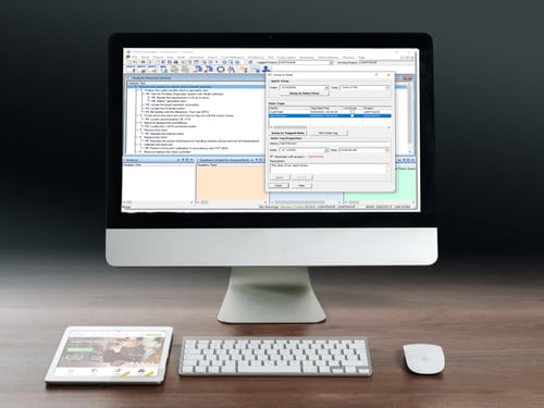 A computer monitor displaying the VISION Developer software interface on the screen, with various open windows and toolbars. In front of the monitor its a white keyboard and a mouse on a desk, alongside a digital tablet. 