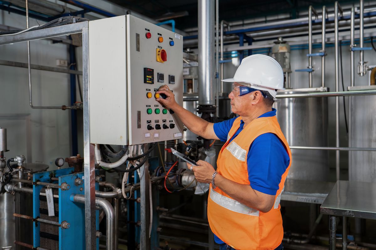 Technician operating plant controls with a tablet in hand