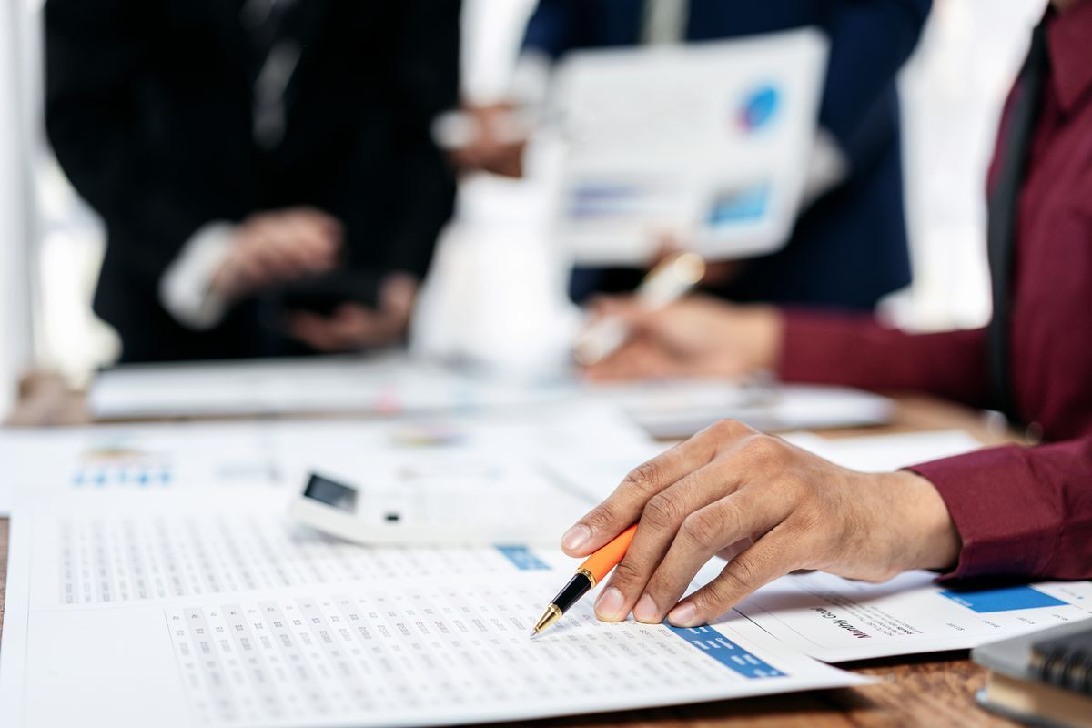 Three people reviewing printed records and charts across a table