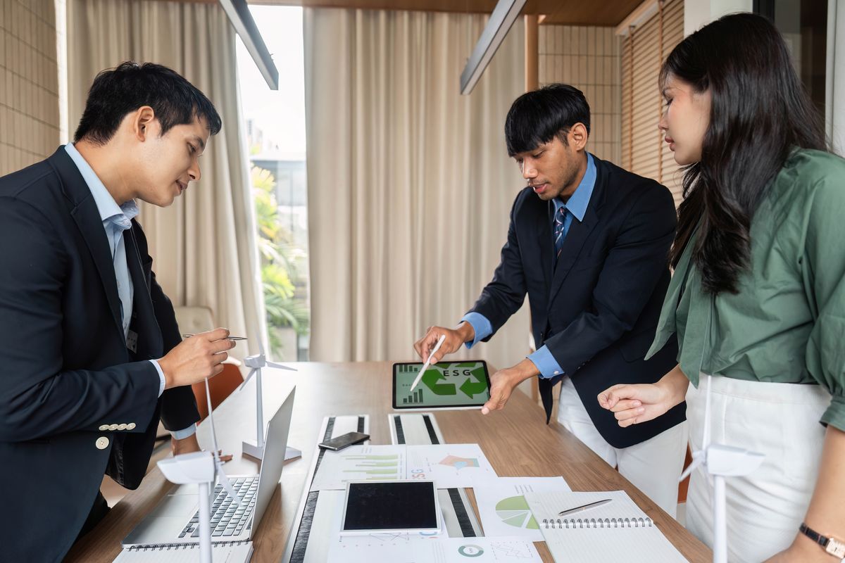 Three people reviewing plans with wind turbine models on the table