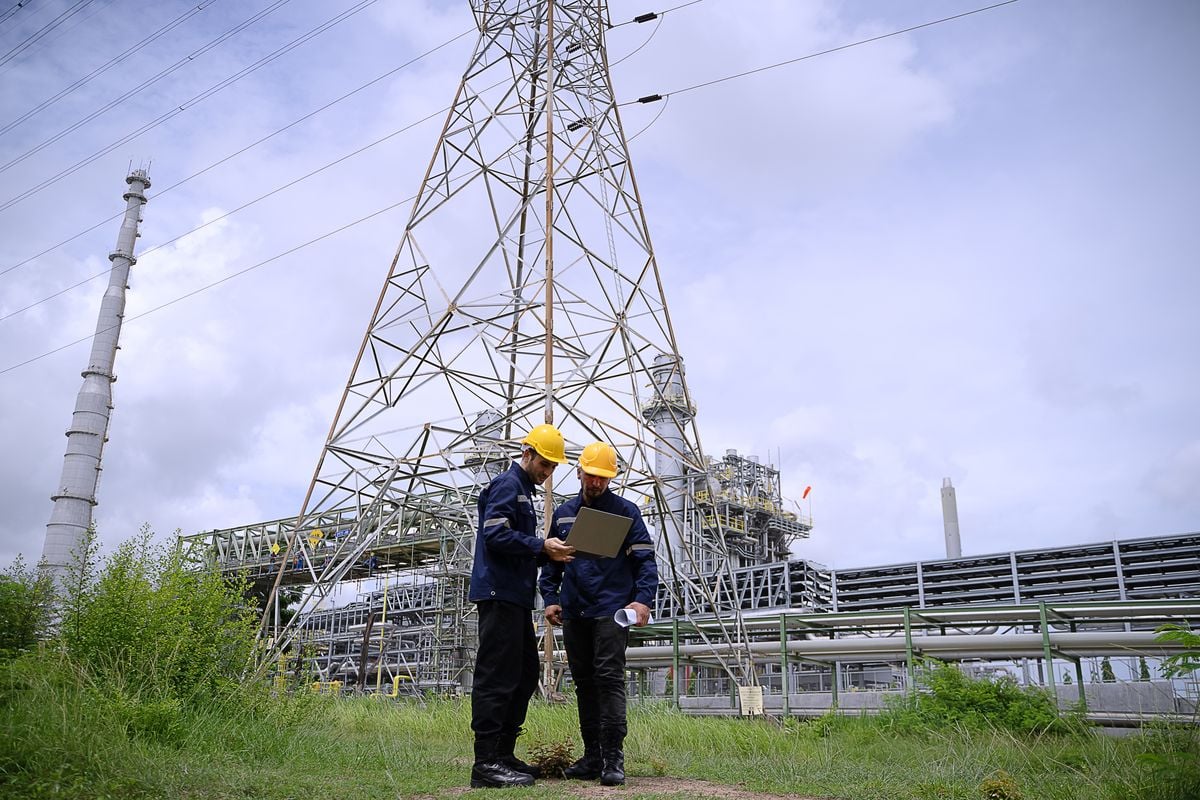 Two technicians reviewing records beside a transmission tower