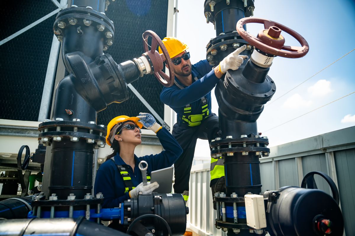 Two technicians working on valves above a plant deck
